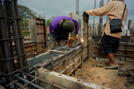 Workers welding the steel for supporting the mold of concrete structure at the construction siteの写真素材