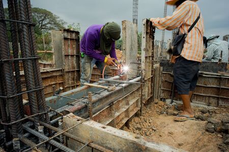 Workers welding the steel for supporting the mold of concrete structure at the construction siteの写真素材