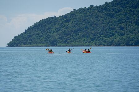 Selective focus on group of travelers canoeing on the surface of sea for touring with seascape and island inbackgroundの写真素材