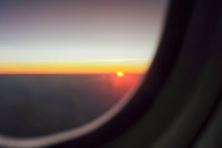 Light of sunset on the skyline with blue sky background and shadow of aircraft window in foreground