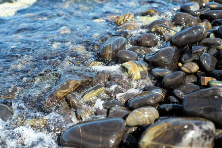 Closeup group of wet polished stones and pebbles were surfed by the seaの写真素材
