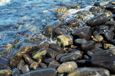 Closeup group of wet polished stones and pebbles were surfed by the seaの写真素材