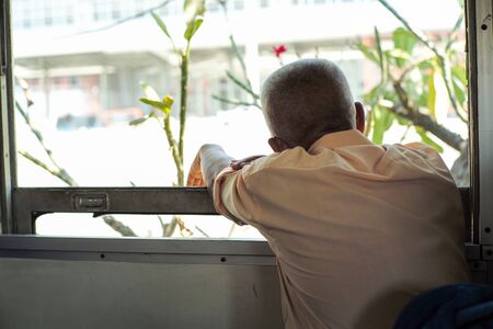 Back portrait of lonely old man sits in the train and looks out of windowの写真素材