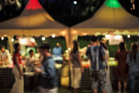 Blurred motion people walk in the food festival at night with decorative bokeh light in backgroundの写真素材