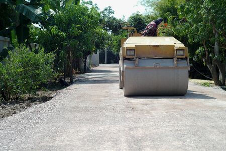 Worker drives the road roller on the crash stone road for preparaing the surfaceの写真素材