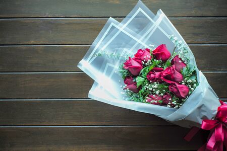 Top view bouquet of blossom red rose inside the white paper on the wooden table. Valentine's dayの写真素材