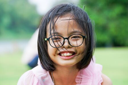Closeup smiling face of Asian girl looking at the camera with blurred natural backgroundの写真素材