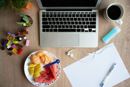 Top view of laptop on the wooden desk with stationaries and coffee with mixed fruit. Work from home. Quarantine at homeの写真素材