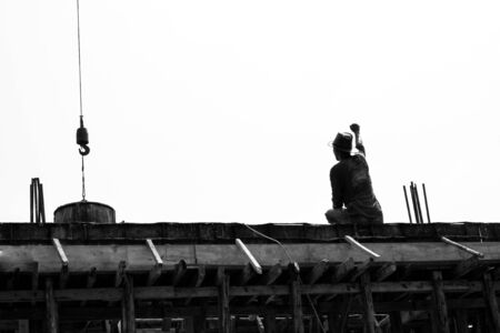 Monochrome back portrait of worker sending the hand signal to the colleague for pouring the mixed concrete at the construction siteの写真素材