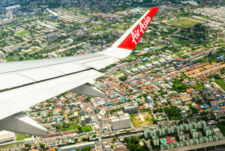 Closeup wing of airplane while flying in the air with cityscape belowのeditorial素材