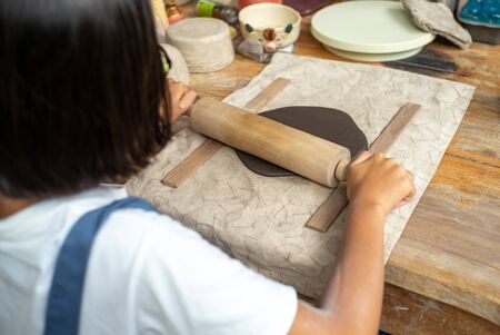 Closeup hands of girl uses the rolling pin on the clay during molding workshop classの写真素材