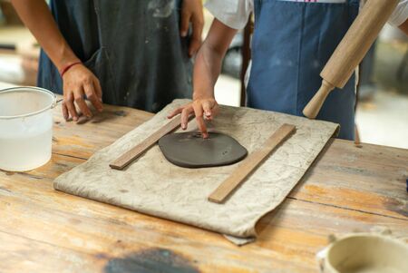 Closeup hands of girl uses the rolling pin on the clay during molding workshop classの写真素材