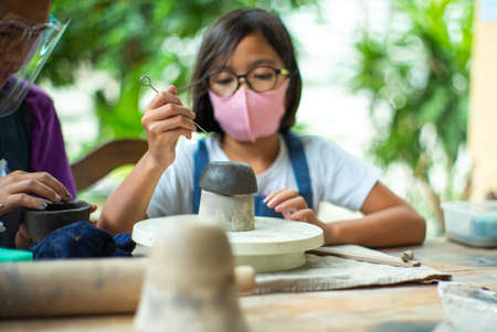 Closeup clay work with blurred little student learning in the workshop class. Classroom with new normal conceptの写真素材