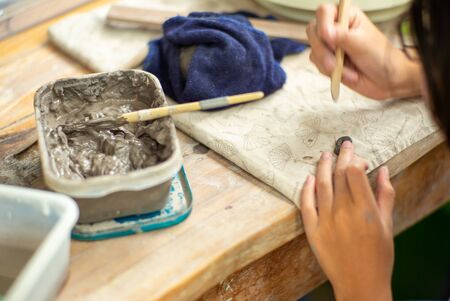 Motion blurred hands of girl molding the clay work with wet mud in plastic trayの写真素材