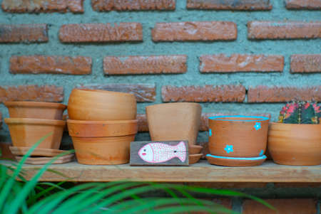 Closeup empty clay pot on the wooden shelf with blurred bricklayer wall backgroundの写真素材