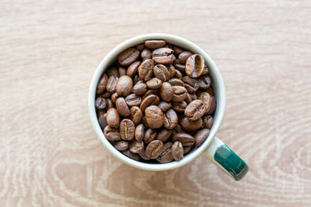 Closeup top view of many coffee beans in the ceramic mug with copy space for adding some textの写真素材