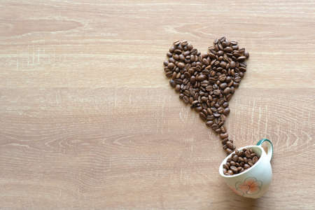 Many roasted coffee beans put of the ceramic cup into heart shapeの写真素材