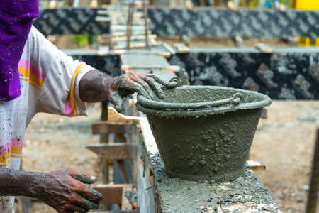Closeup dirty bucket coated by the wet cement with motion blurred of worker at the construction siteの写真素材