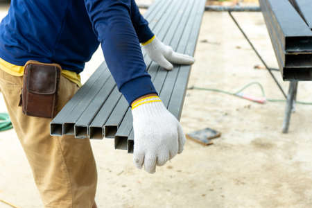 Closeup hands of workman holding the steel bar at the construction siteの写真素材