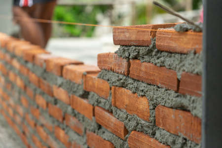 Closeup red bricklayers wall built on the cement at the construction site