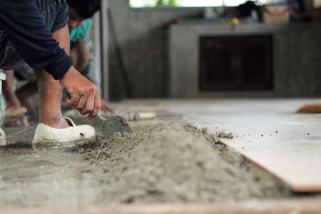 Motion blurred of hand installing the floor tiles by trowel at the construction siteの写真素材