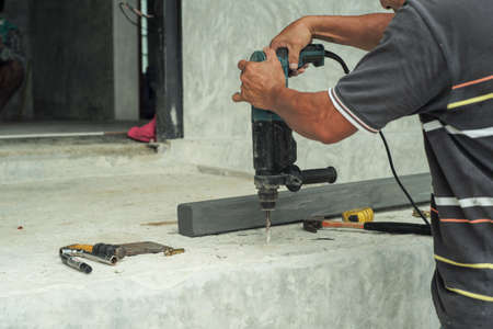 Selective focus on the hands of worker hold the drilling machine during drilling on the cement floor at the construction siteの写真素材