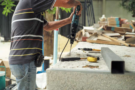 Selective focus on the hands of worker hold the drilling machine during drilling on the cement floor at the construction siteの写真素材