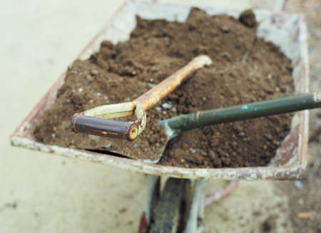 Closeup rusted holder of a shovel in the wheelbarrow with pile of soil in backgroundの写真素材