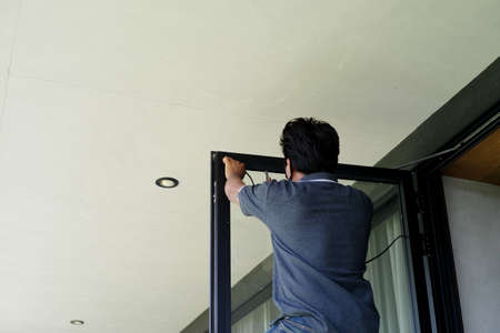 Back portrait of worker repairs the door frame