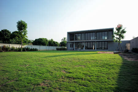 Exterior of house in modern style with grass field and garden at the backyardの写真素材
