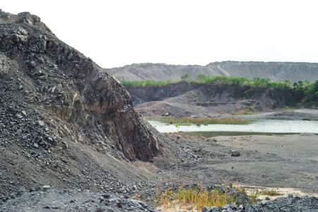 Closeup pile of crushed stone in the outdoor mine with blurred mountain and small lake in backgroundの写真素材