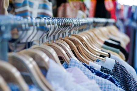 Closeup fashionable clothes on the wooden hangers hanging on the rack for sale in the shop at the...