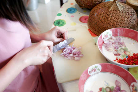 Closeup sliced pieces of shallot on the cutting board with motion blurred of hand shredding the shallot.の写真素材
