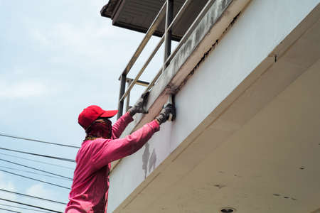 Side view of worker removing the old color out of the surface of the cement wallの写真素材