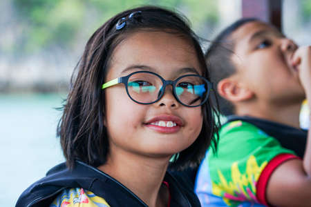 Closeup portrait of cute Asian girl with eyeglasses smiles and looks at the cameraの写真素材
