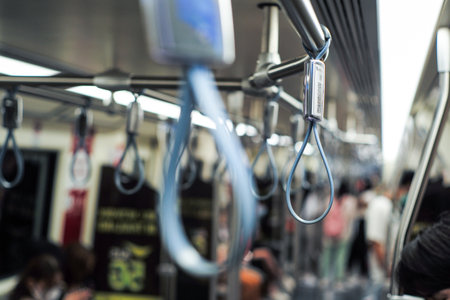 Selective focus on the handrail inside the subway train with blurred group of passengers in...