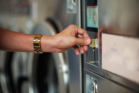 Selective focus on the hand inserts the coin into the vending machine for washing the clothes at the self service shopの写真素材