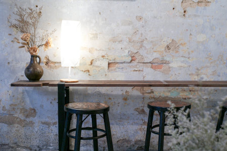 Set of vintage wooden chairs and table decorated by the modern lighting lamp and dried flowers in the vase with old white wall backgroundの写真素材