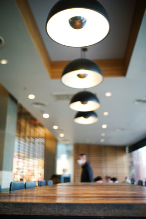 Closeup the edge of wooden table in the cafe with blurred background of modern interior design room...