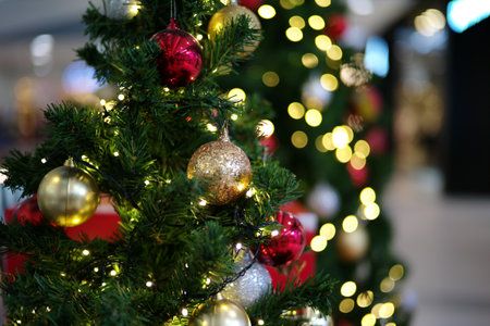 Selective focus on the golden ball decorated on the Christmas tree with the bokeh lights in background. Party and celebration in Christmas festivalの写真素材