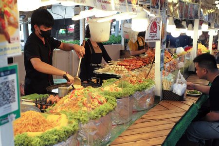 Bangkok, Thailand:March5,2023-Chefs cooking in the street food shop with defocused group of tourists waiting for the food in foregroundのeditorial素材