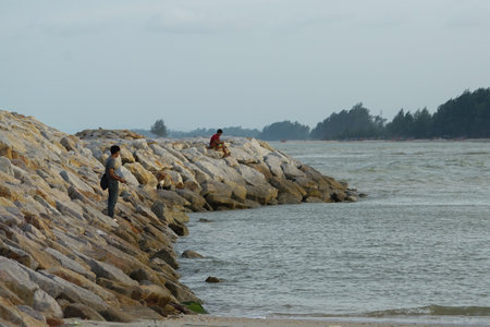 The people fishing at the coast of the sea by the fishing rod with seascape in backgroundの写真素材