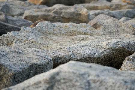 Selective focus on the rough surface of stone with blurred foreground and seascape backgroundの写真素材