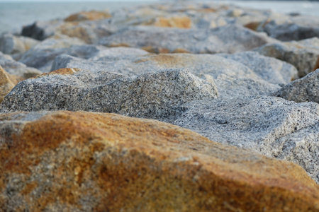 Selective focus on the rough surface of stone with blurred foreground and seascape backgroundの写真素材