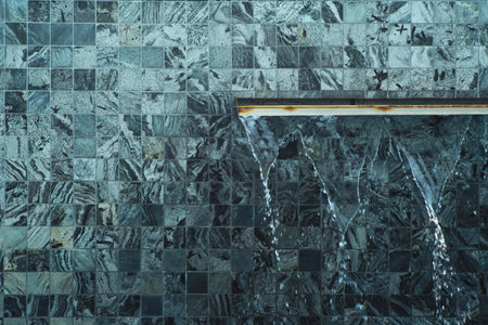 The pouring water from the wall with random design of tilesの写真素材