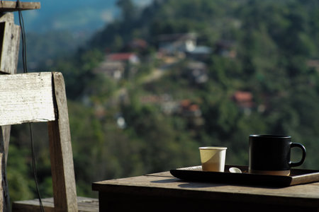 A cup of hot black coffee on the wooden table at the coffee shop on the hill with blurred mountain in backgroundの写真素材