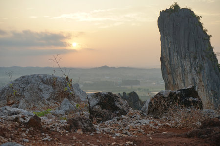 Rock on the top of the mountain with defocused landscape and sunrise sky in backgroundの写真素材
