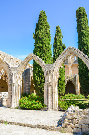 Vertical photography of the inner courtyard with typical arches in Bellapais Abbey in Turkish Northern Cyprus. The historical monastery is a popular tourist attraction. Captured with blue sky.の写真素材