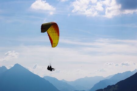 Tandem paragliding in Swiss Alps. Silhouettes of paragliders and beautiful mountains. Extreme sport,...