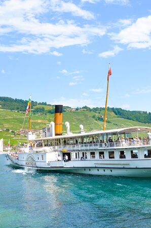 Cully, Switzerland - August 11, 2019: Sightseeing boat with tourists on Lake Geneva. Vineyards on...
